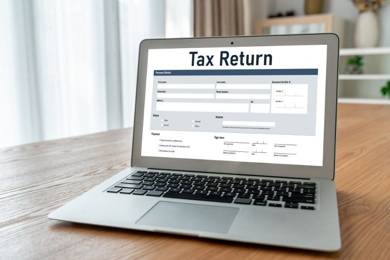 A laptop is open to a tax return form on the screen.