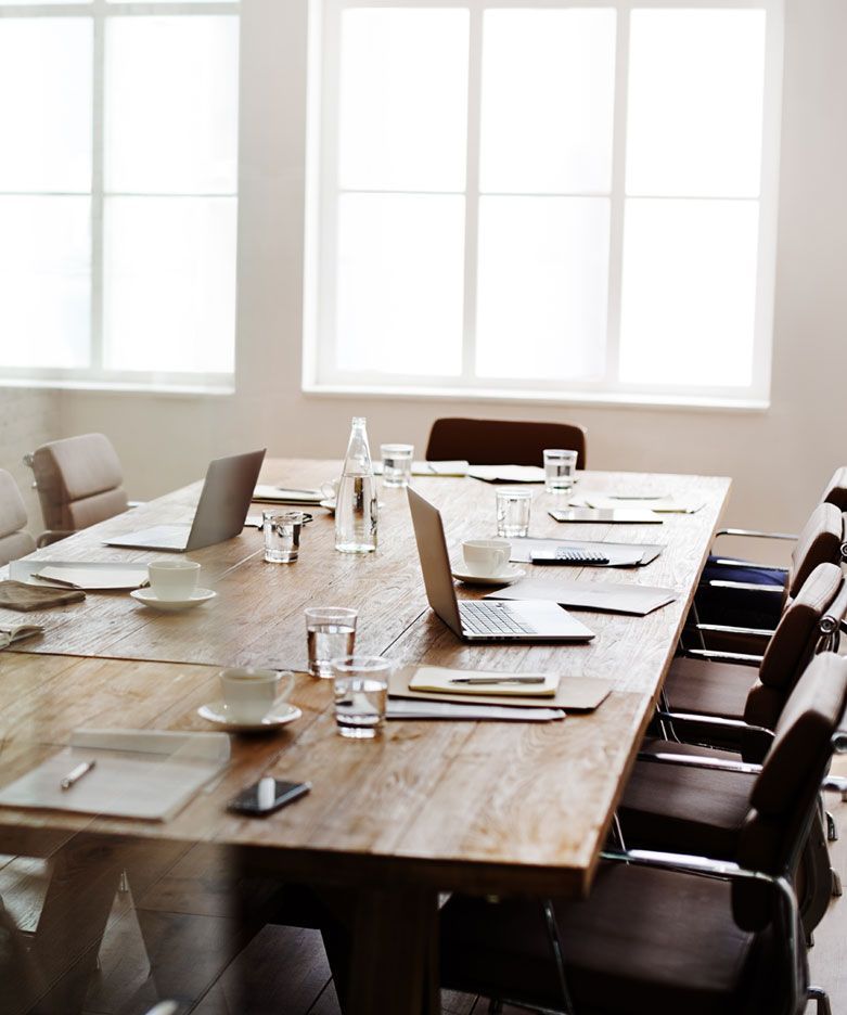 A conference room with a long wooden table and chairs.