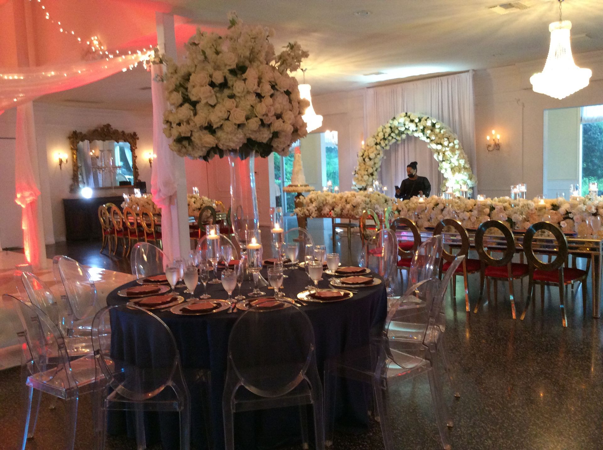 Elegant banquet hall with candlelit tables, floral centerpieces, and a lit archway behind the head table