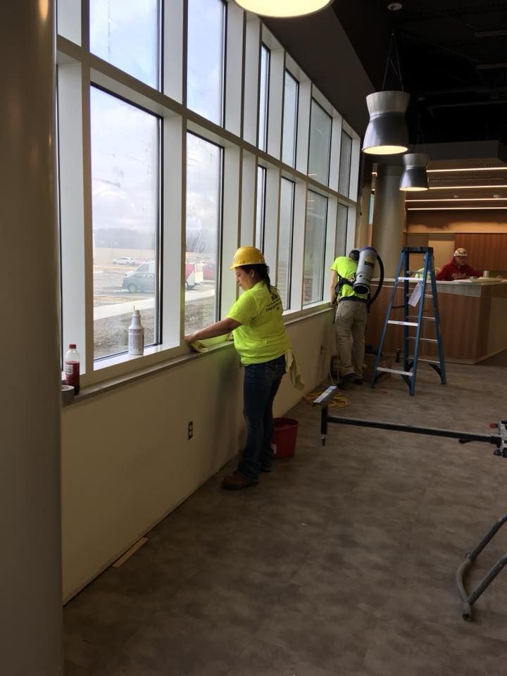 A woman is cleaning a window in a building.