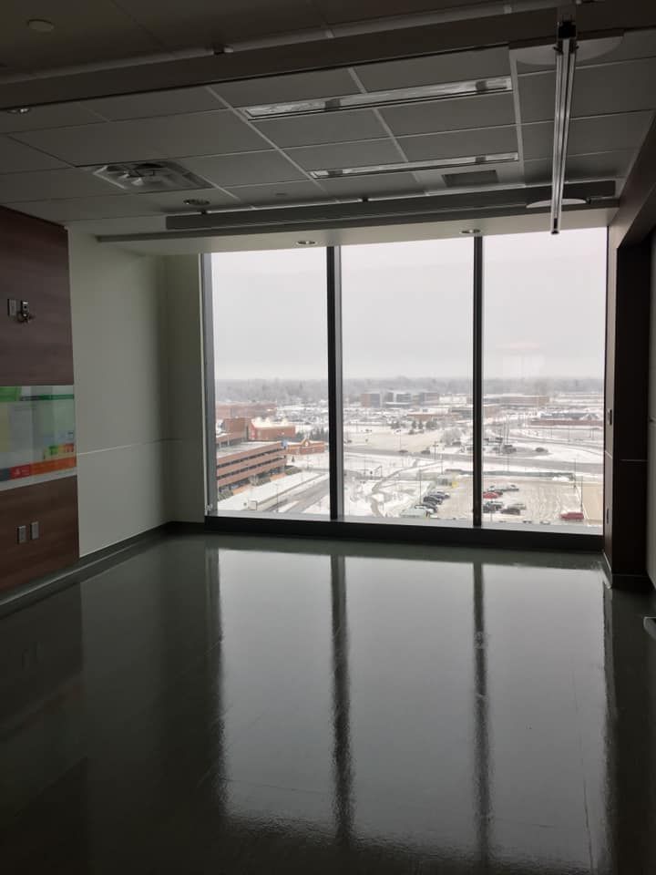 An empty room with a large window and a view of a city.