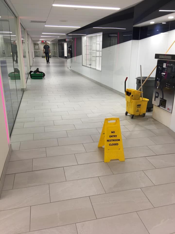 A yellow caution sign is on the floor of a hallway.