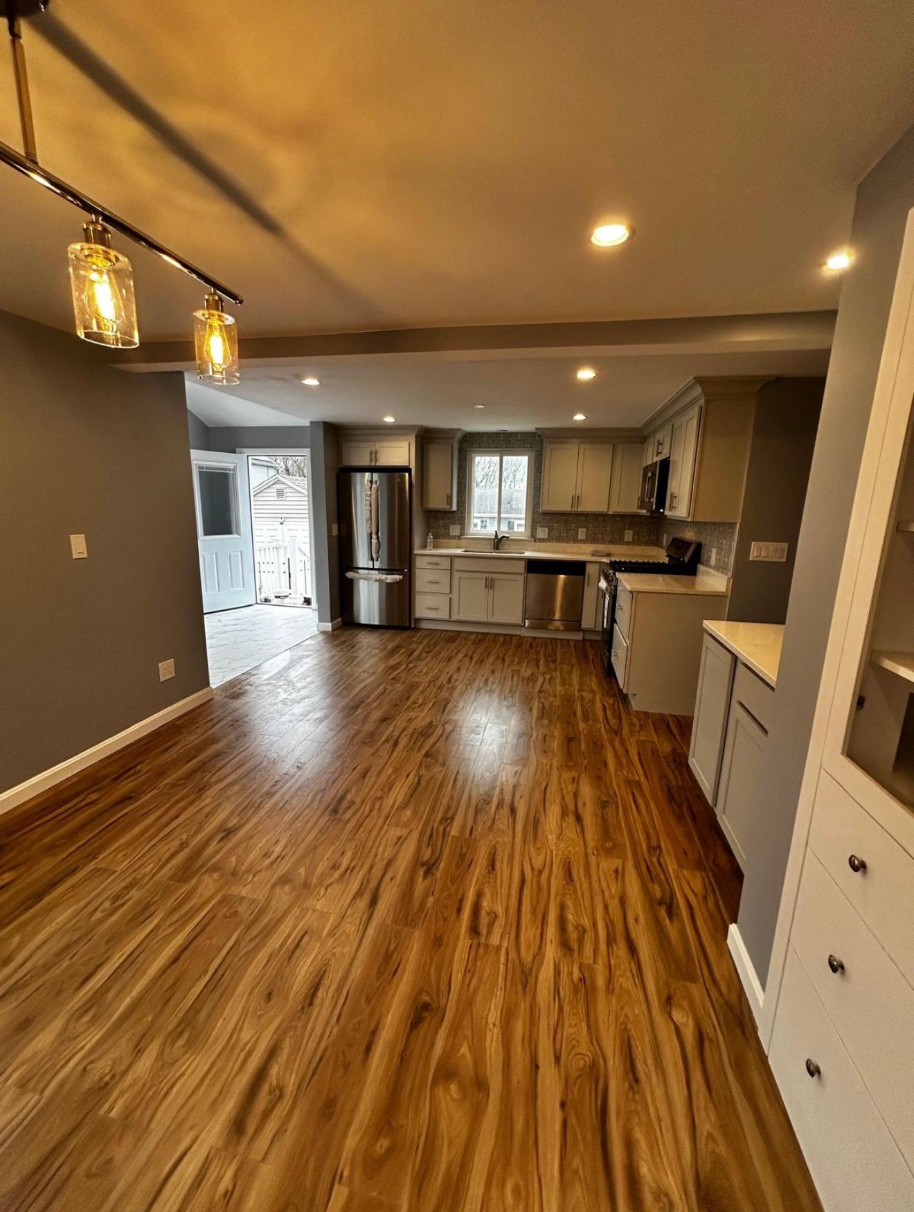 spacious kitchen with wood floors, light gray cabinets, and a stainless steel refrigerator