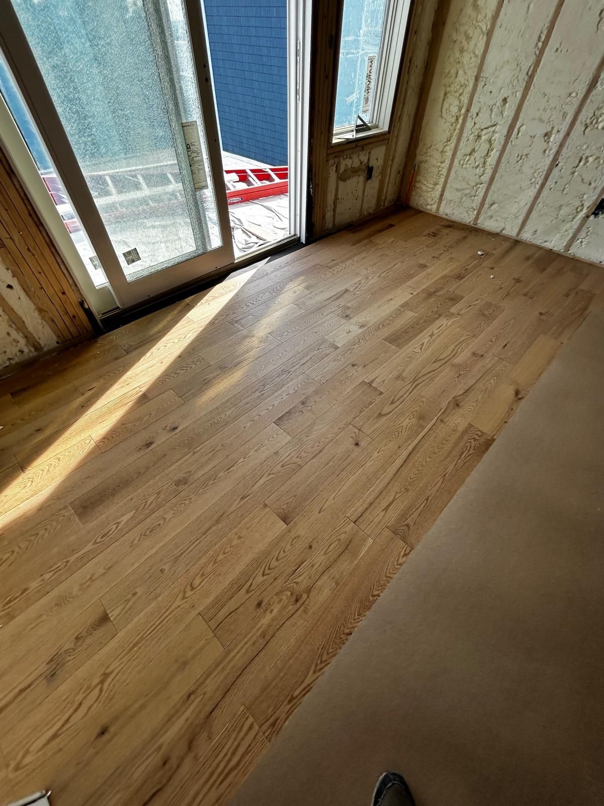 a wooden floor, sunlight streams in from a sliding glass door and a window