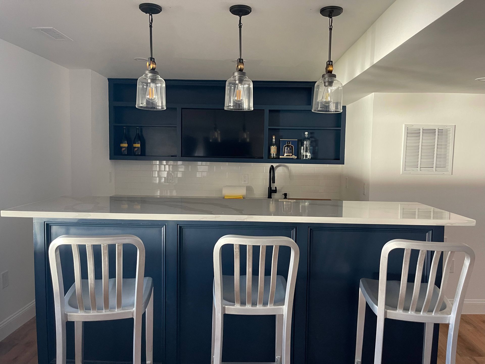A kitchen with a bar and three bar stools