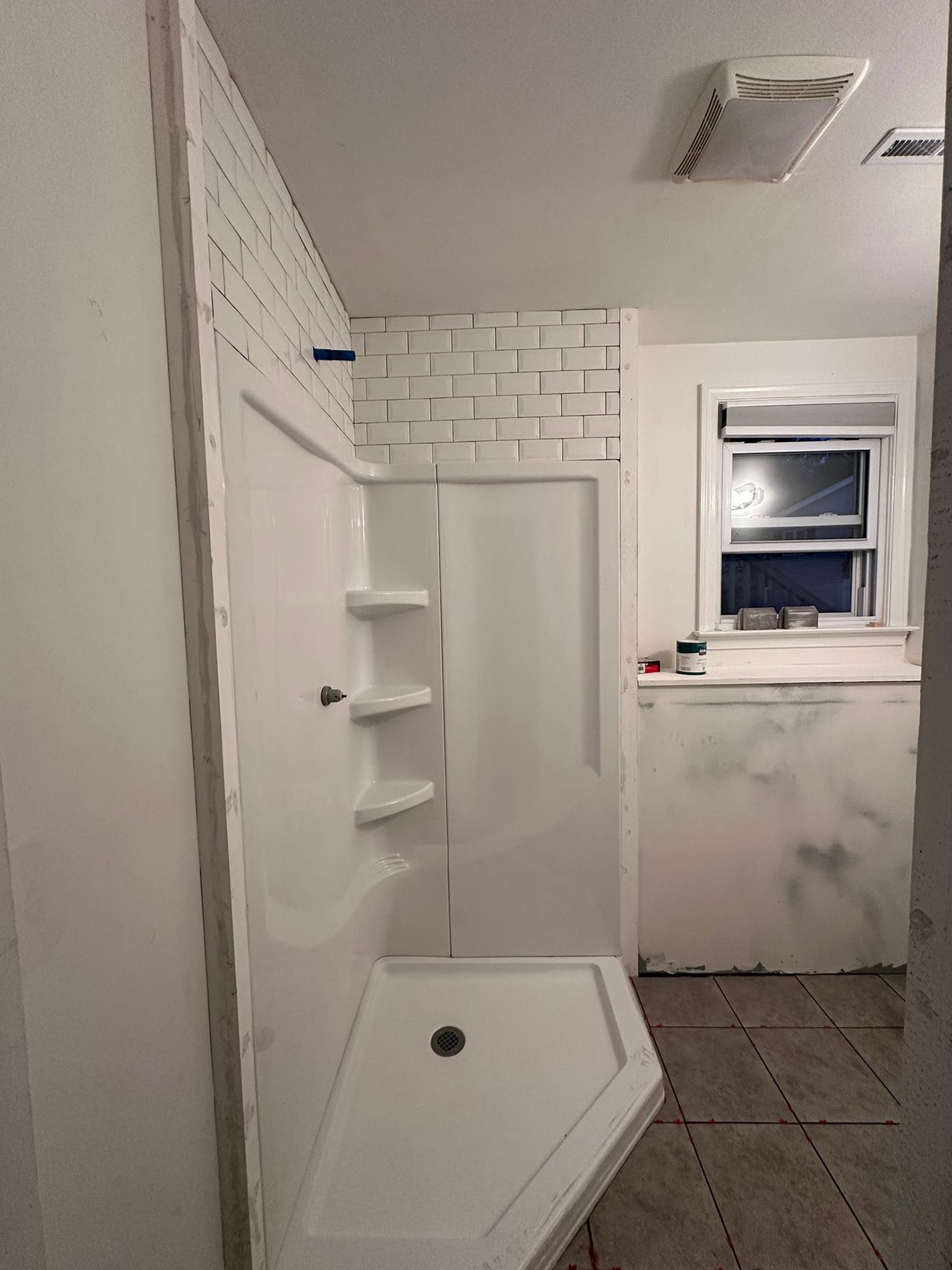A bathroom with a shower stall and a window.