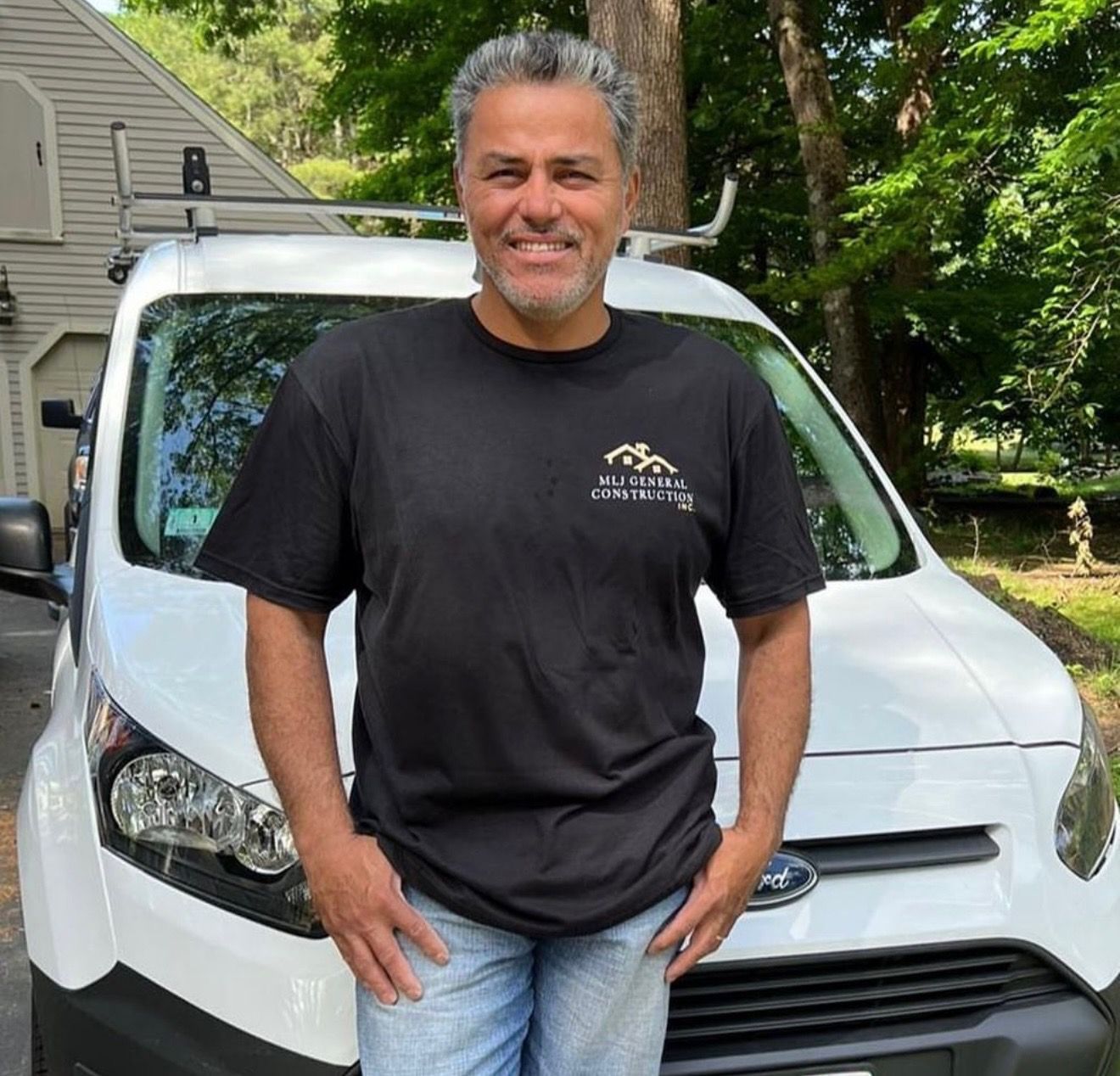 A man in a black shirt is standing in front of a white van.