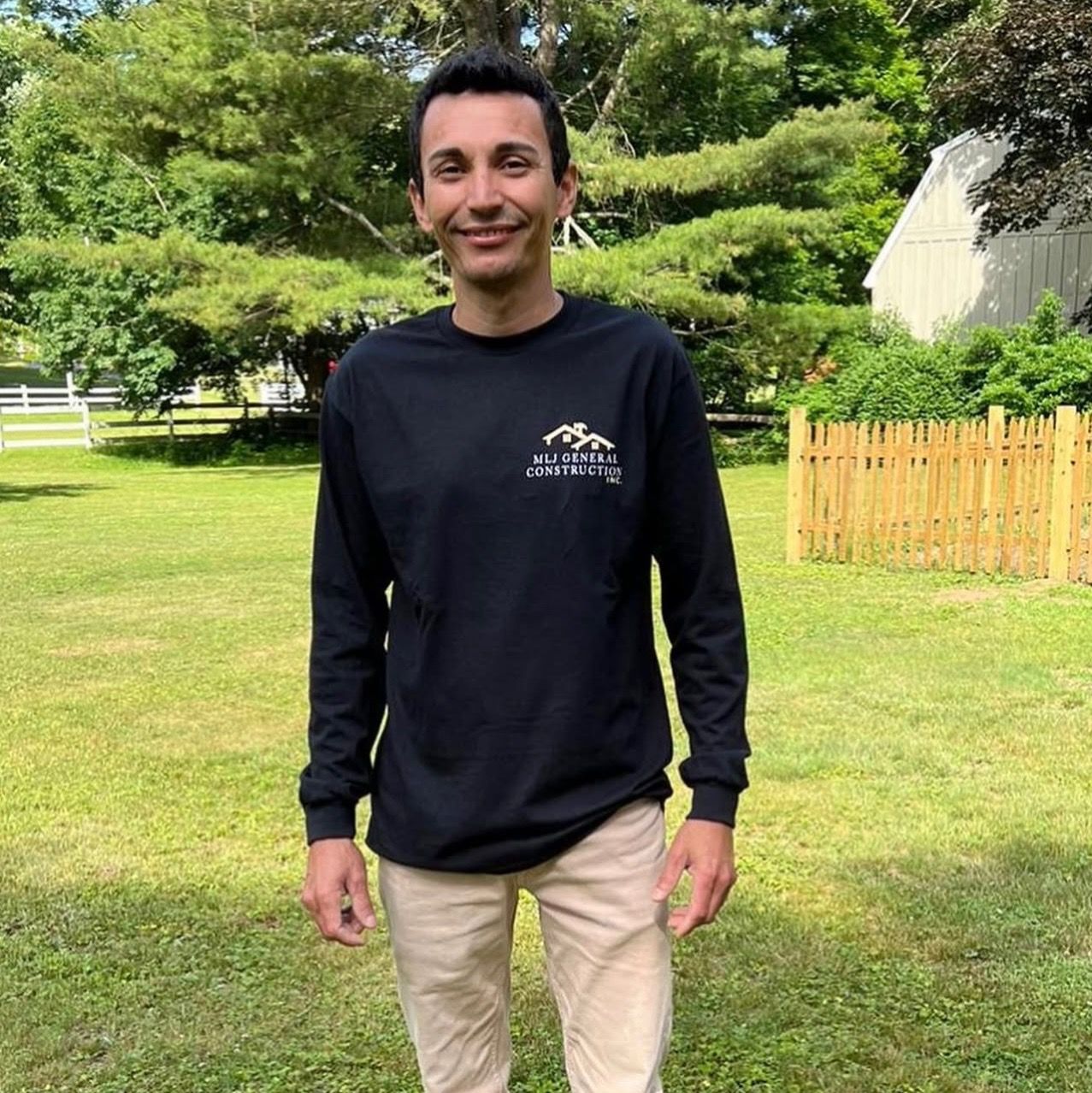 A man in a black shirt is standing in a grassy field
