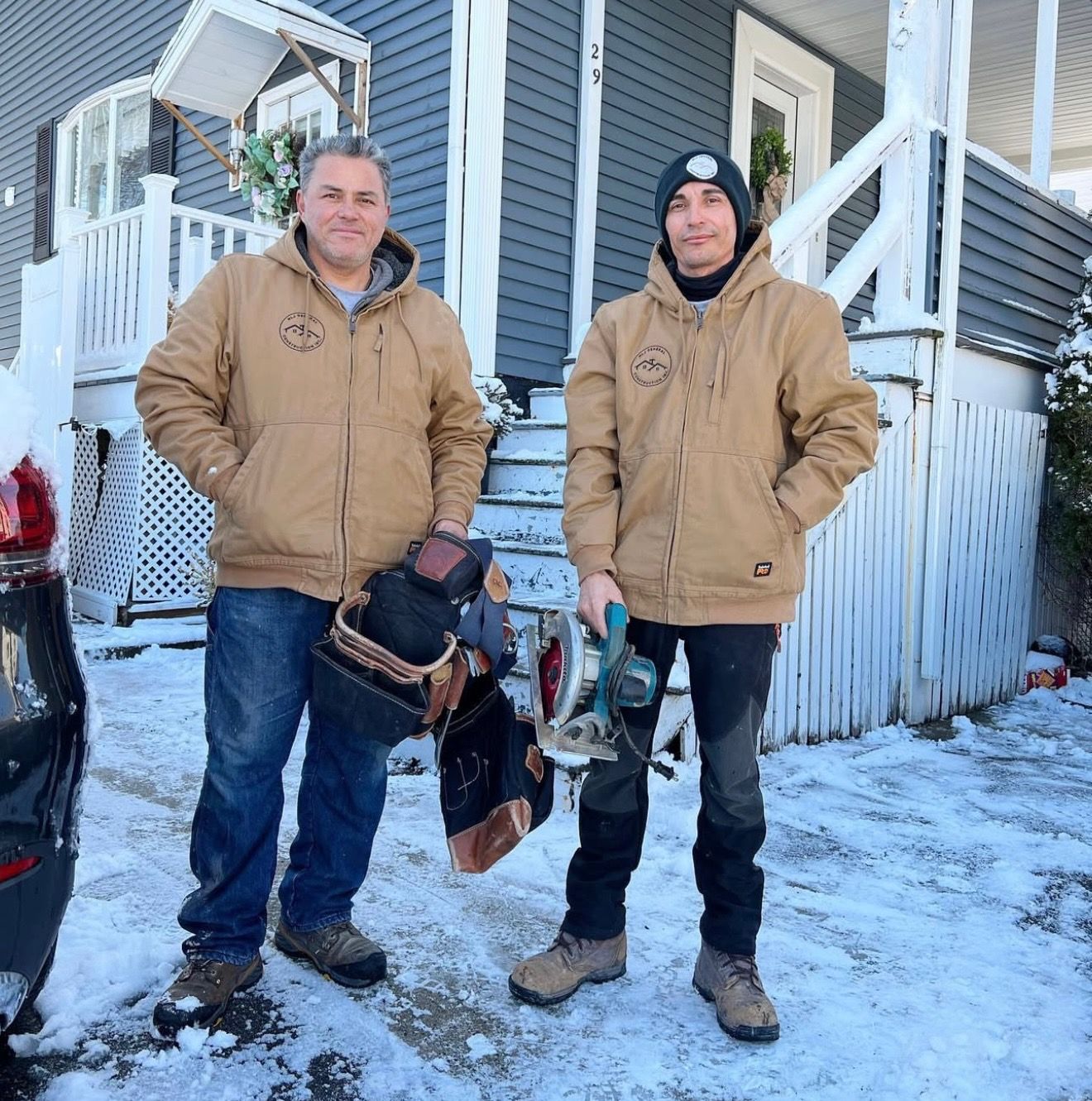 Two men standing in front of a house in the snow