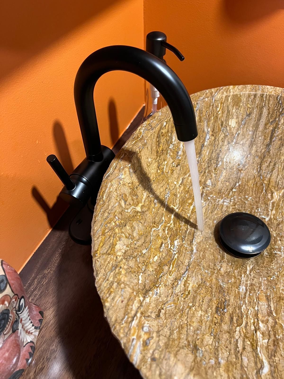 A bathroom sink with a black faucet and soap dispenser