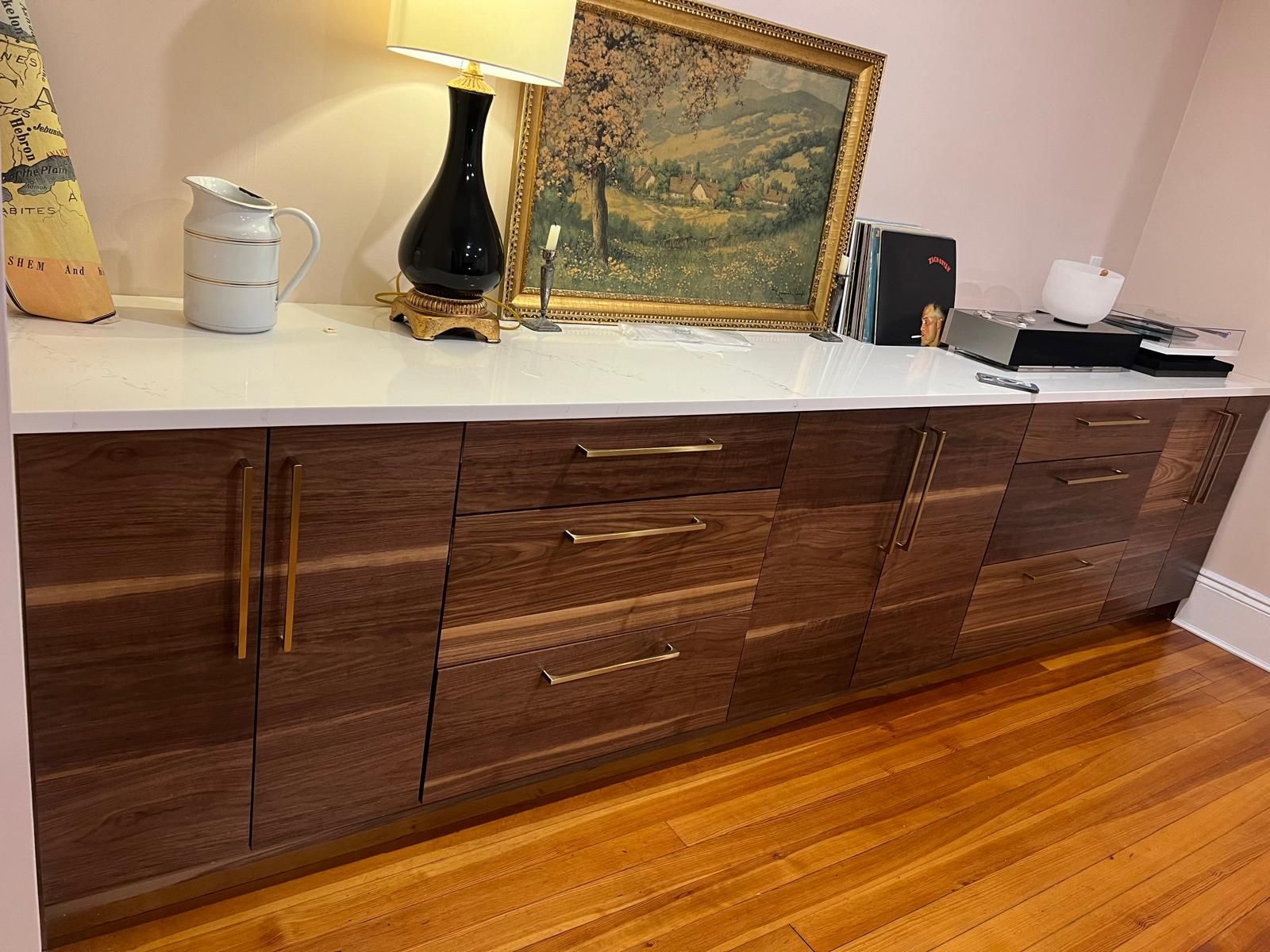 A long wooden cabinet with drawers and a lamp on top of it.