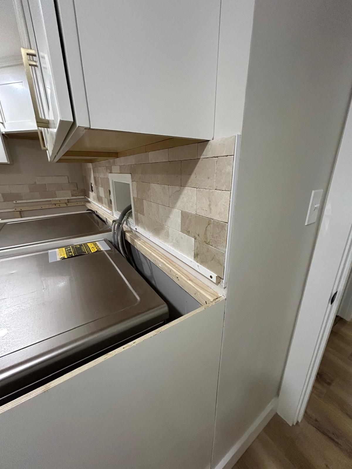 A kitchen with a washer and dryer in the corner.