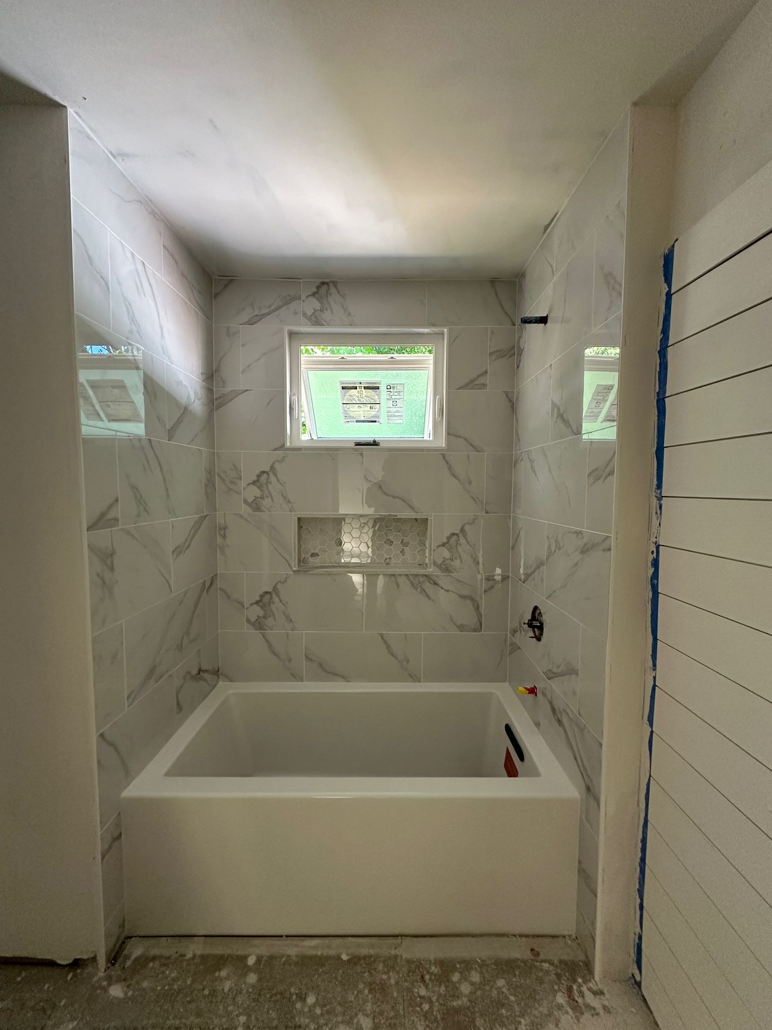 A bathroom with a bathtub and a window.