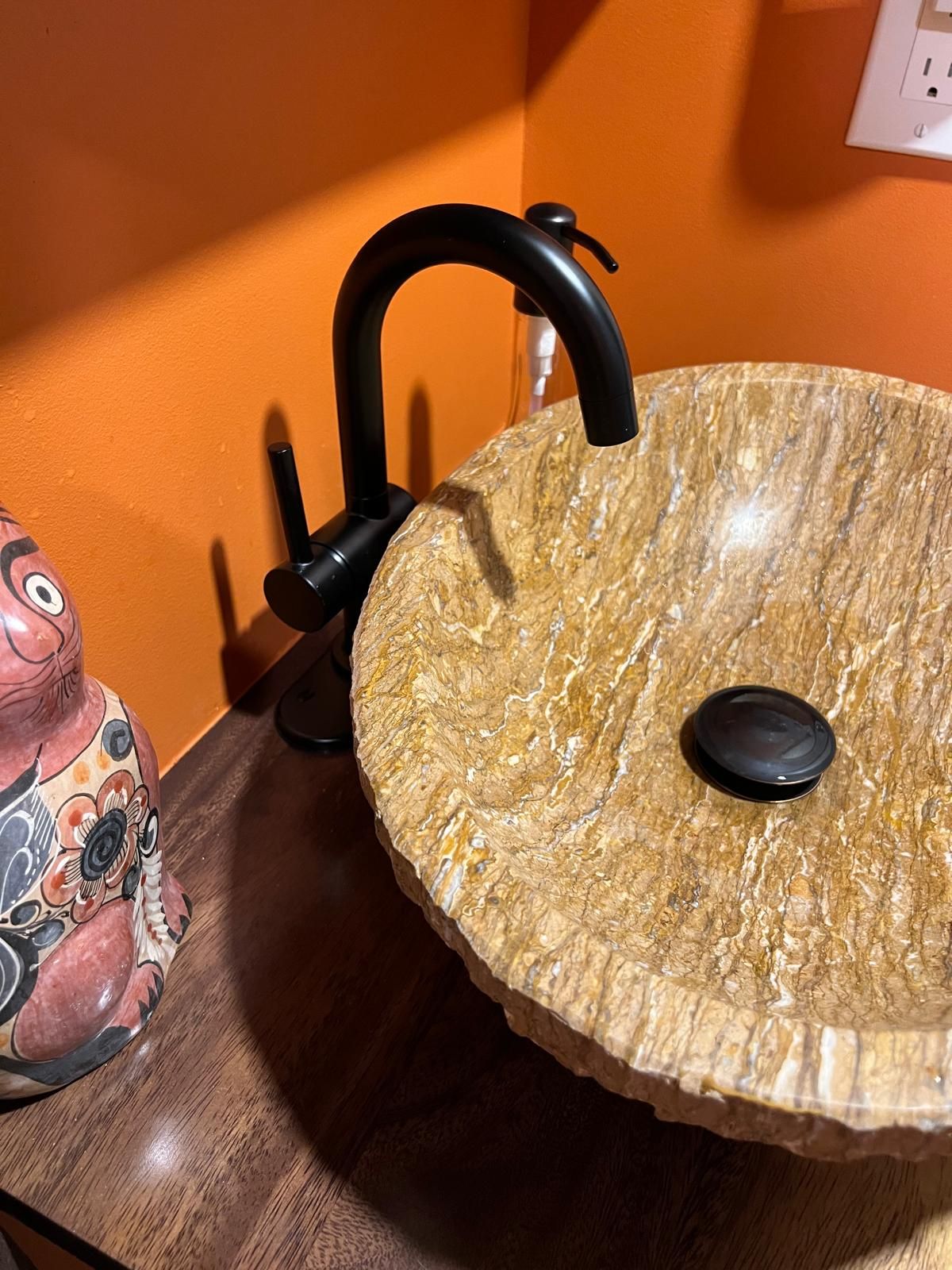 A bathroom sink with a black faucet and a ceramic cat on the counter.