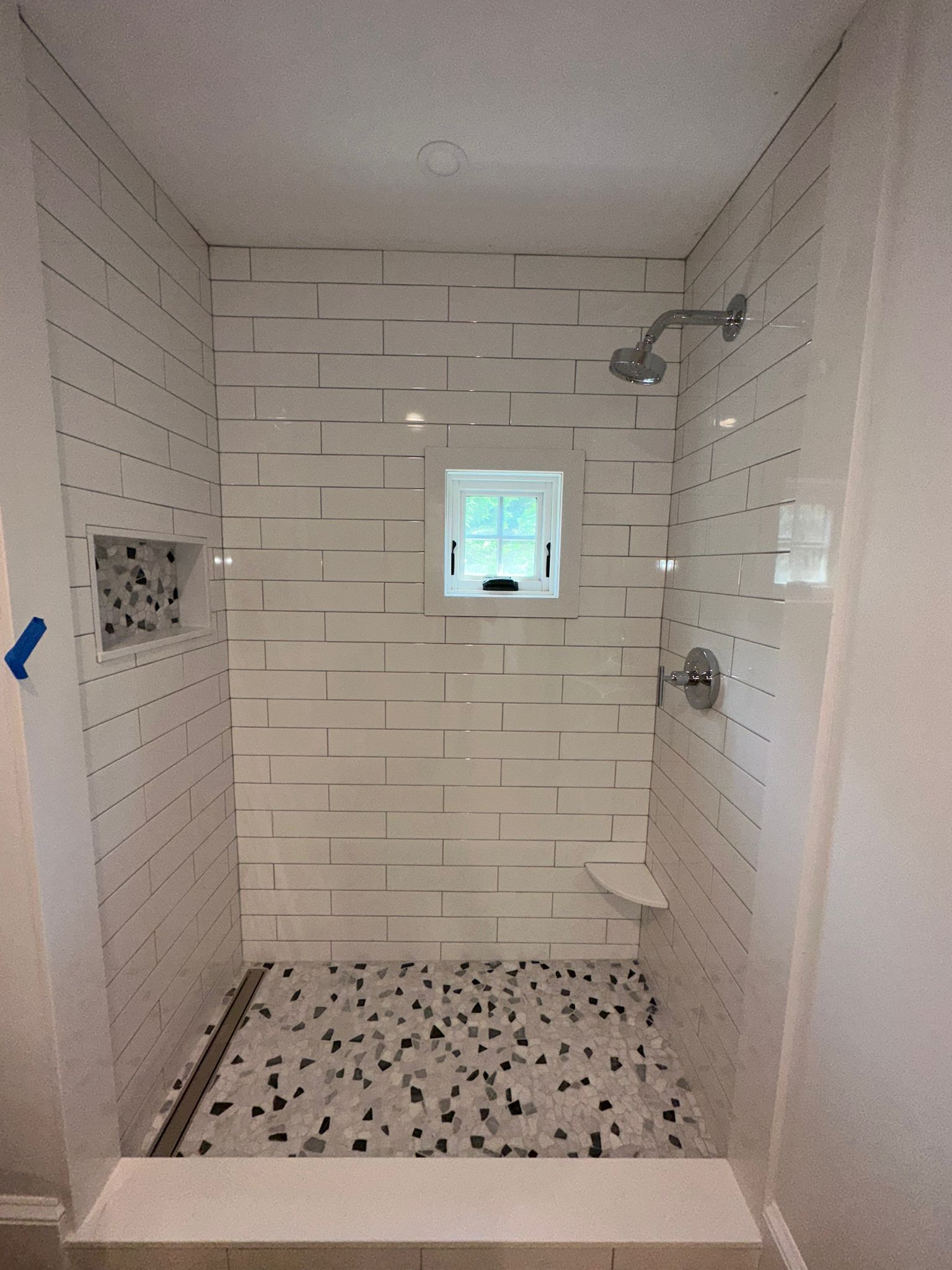 A bathroom with a walk in shower and a window.