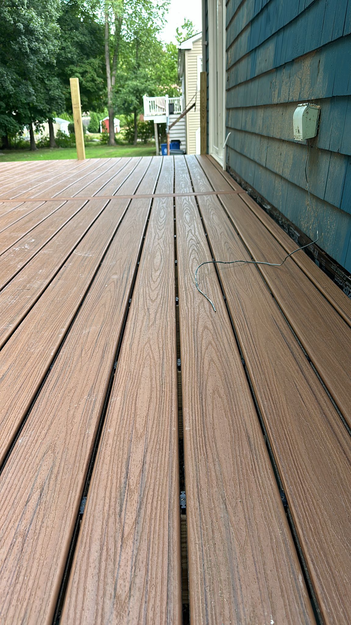 A close up of a wooden deck next to a blue house.