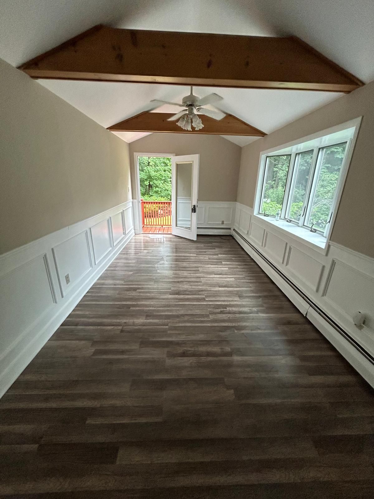 An empty room with hardwood floors and a ceiling fan.