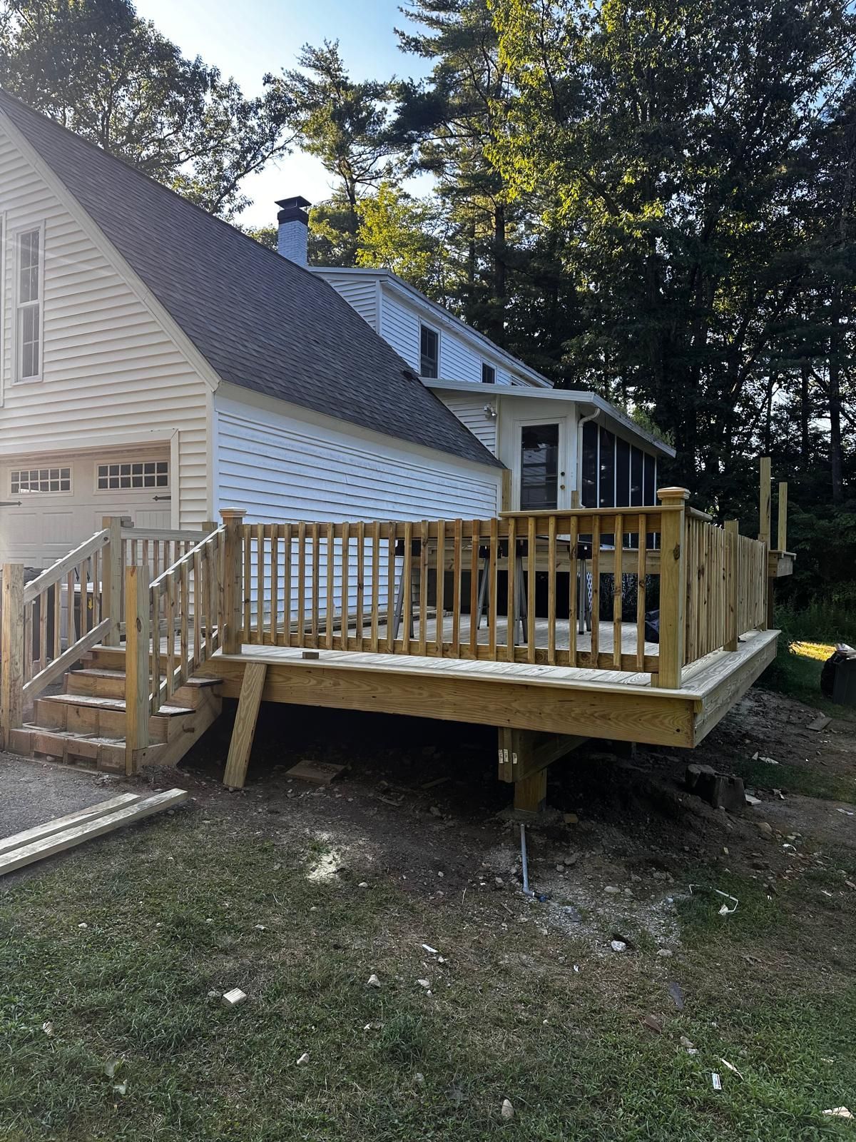 A wooden deck is sitting in front of a house.