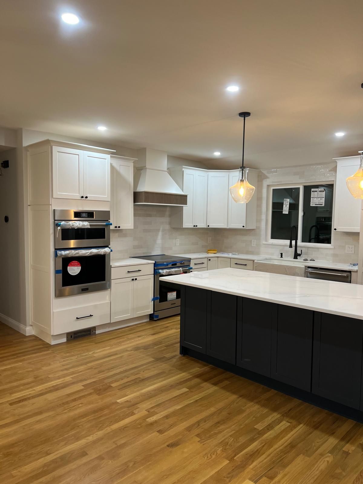A kitchen with white cabinets , stainless steel appliances , and a large island.