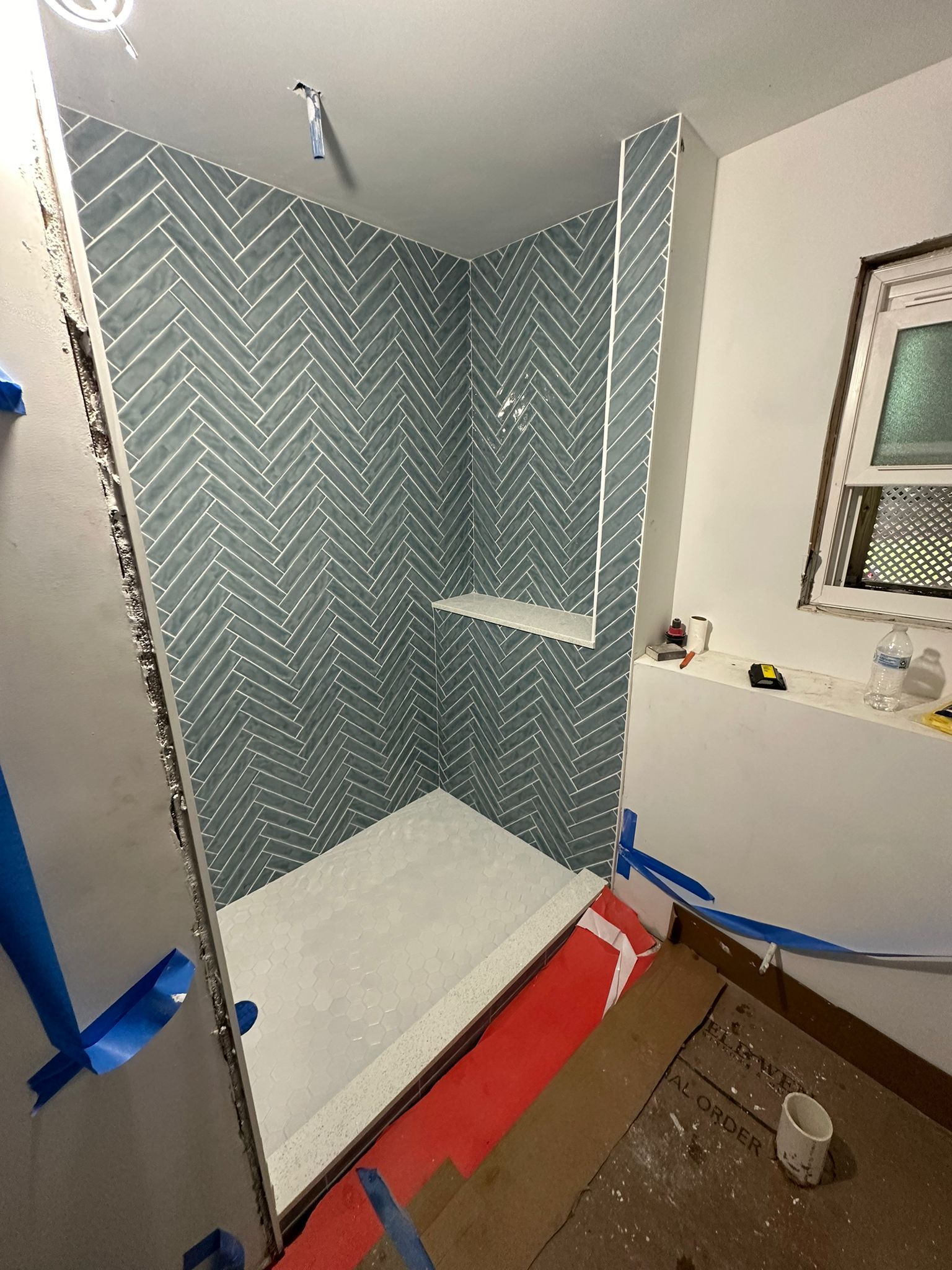 A bathroom with a walk in shower and a window.