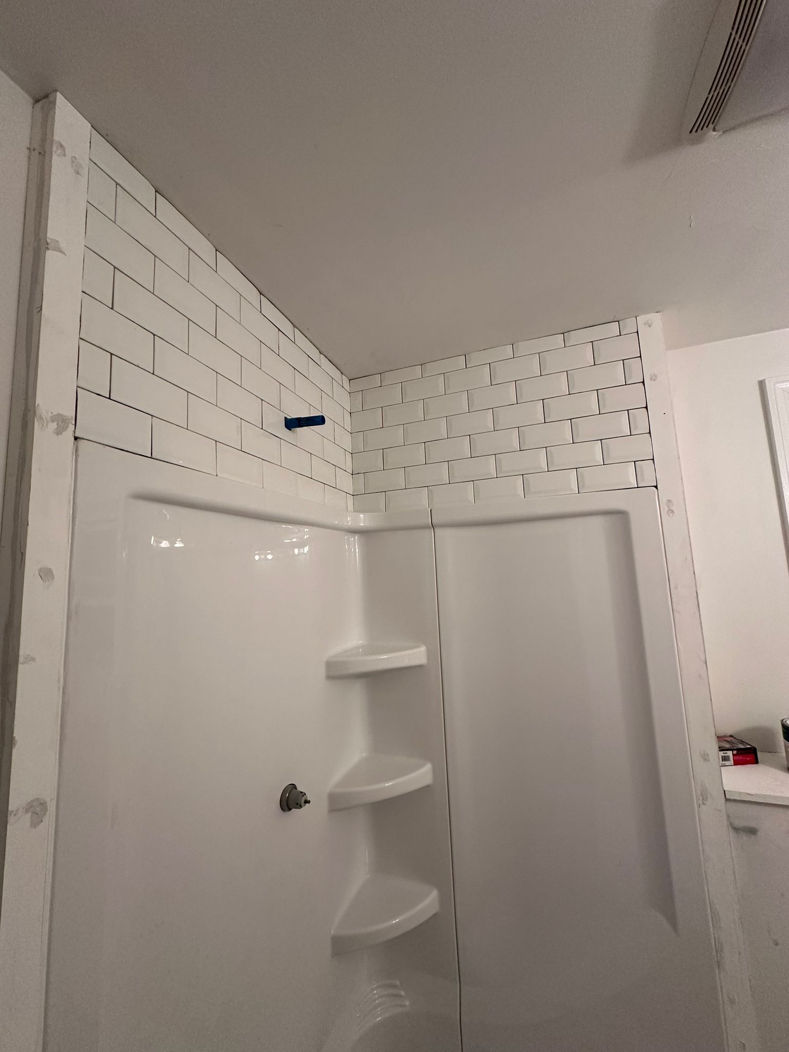 A bathroom with a shower stall and shelves is being remodeled.