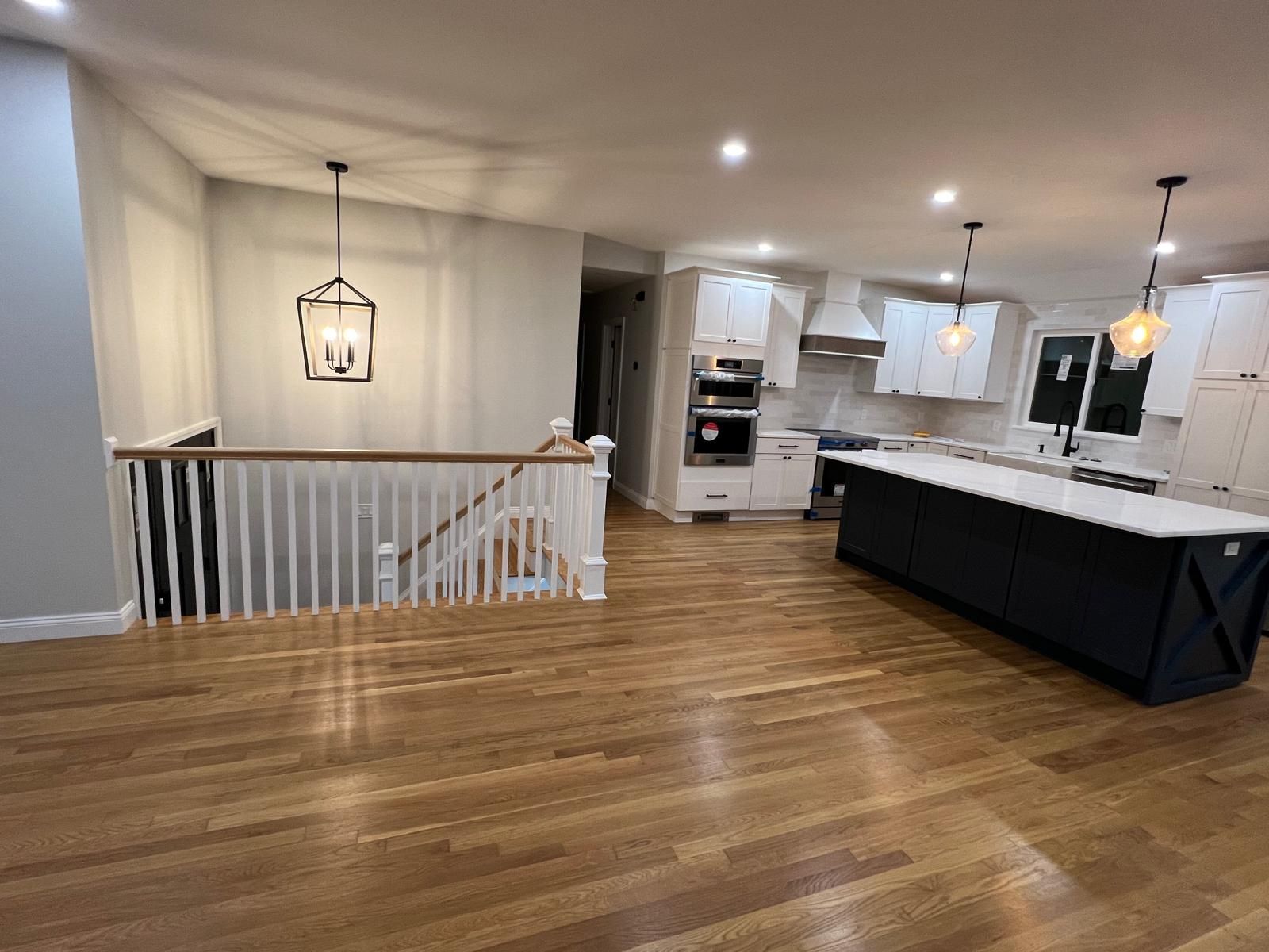 An empty kitchen with hardwood floors and white cabinets