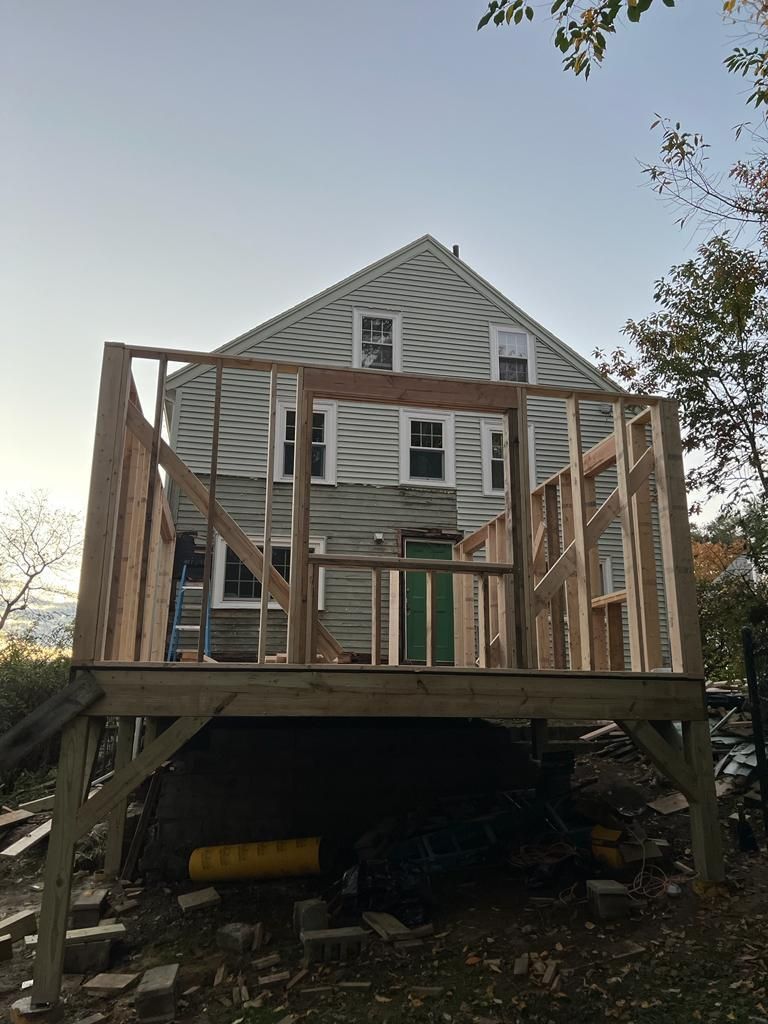 A house with a wooden deck being built on top of it.
