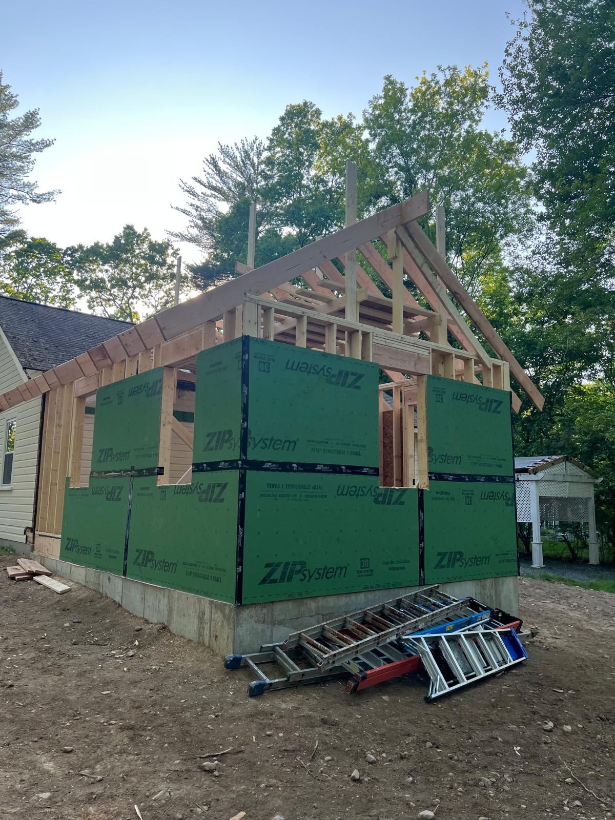 A house is being built with a ladder in front of it.