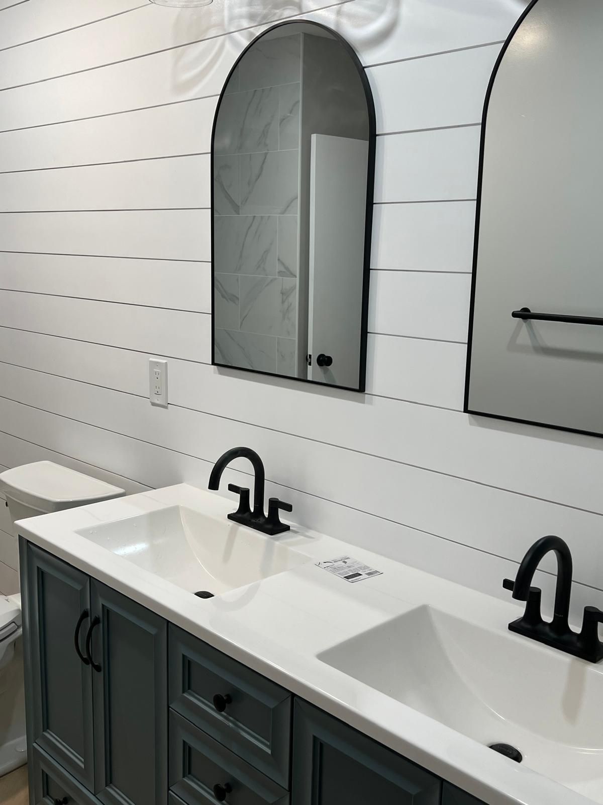 A bathroom with two sinks , two mirrors and a toilet.