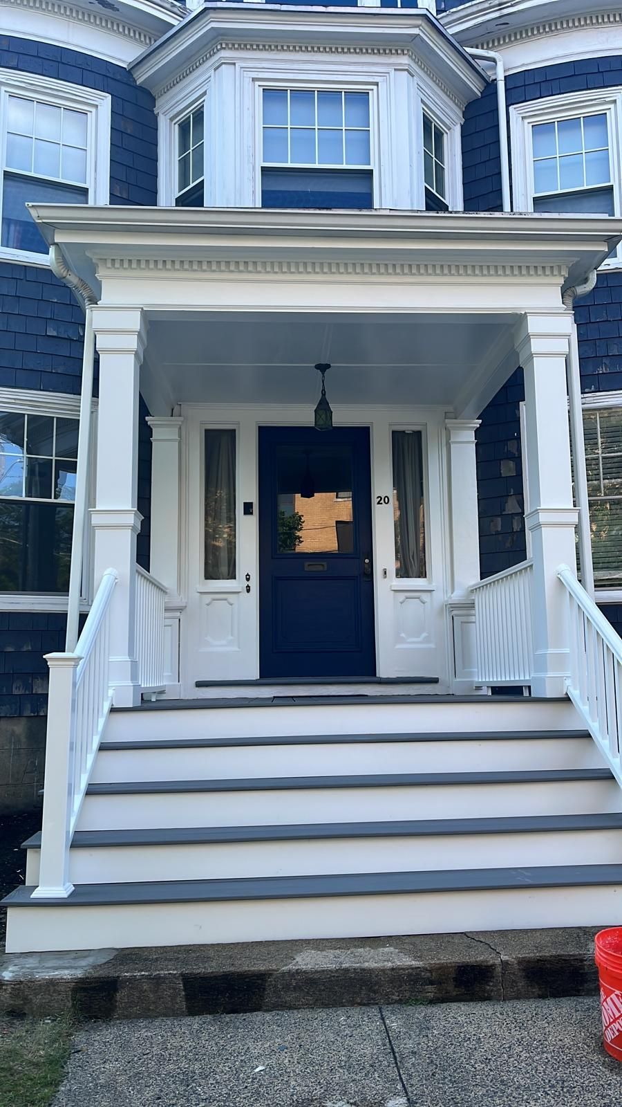The front porch of a blue house with white stairs and a blue door.