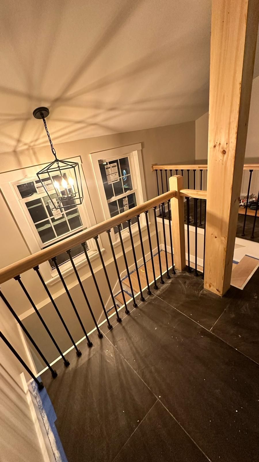 A staircase with a wooden railing and a chandelier hanging from the ceiling.