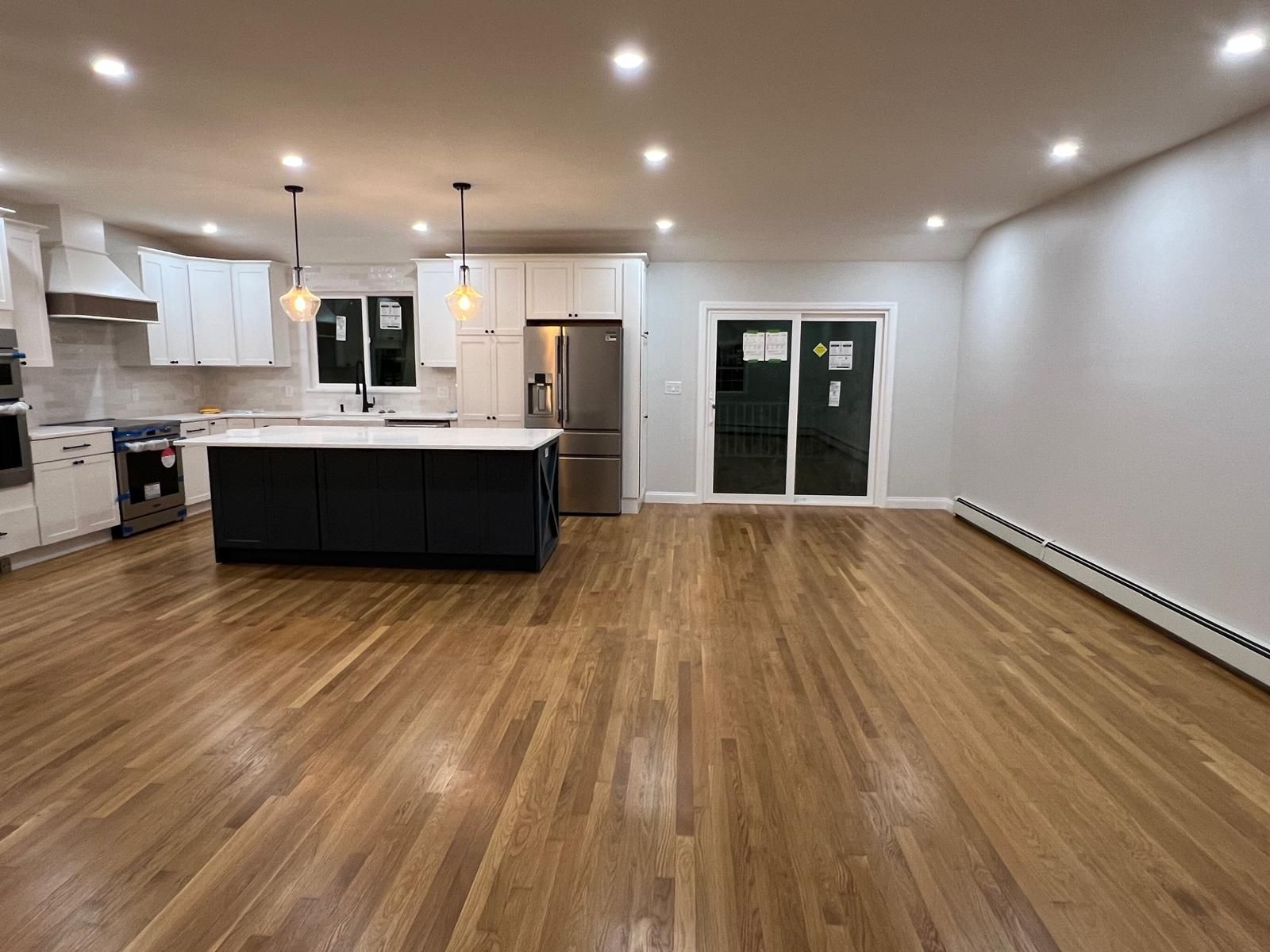 An empty kitchen with hardwood floors and stainless steel appliances.