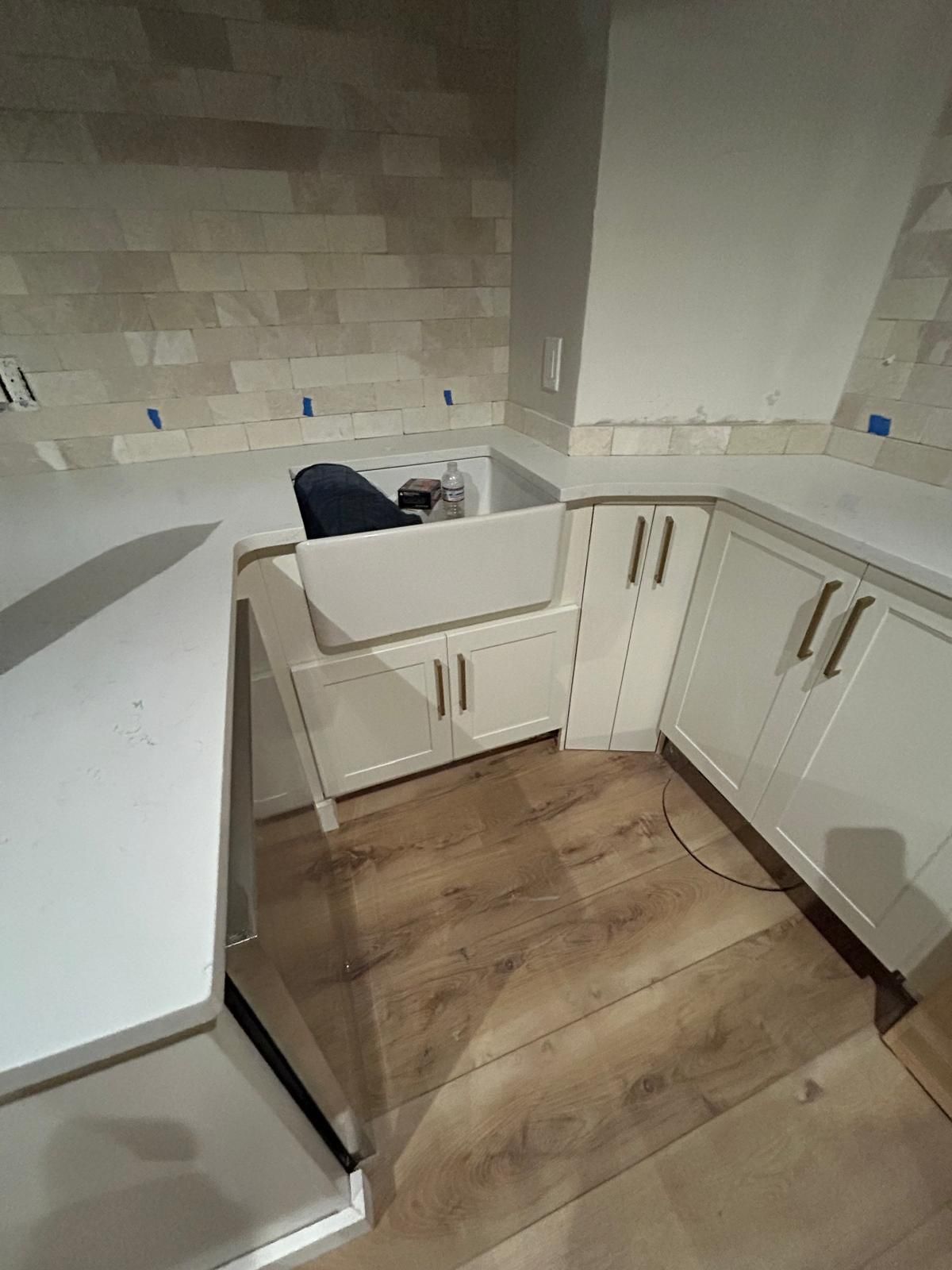 A kitchen with white cabinets and a sink in the corner.