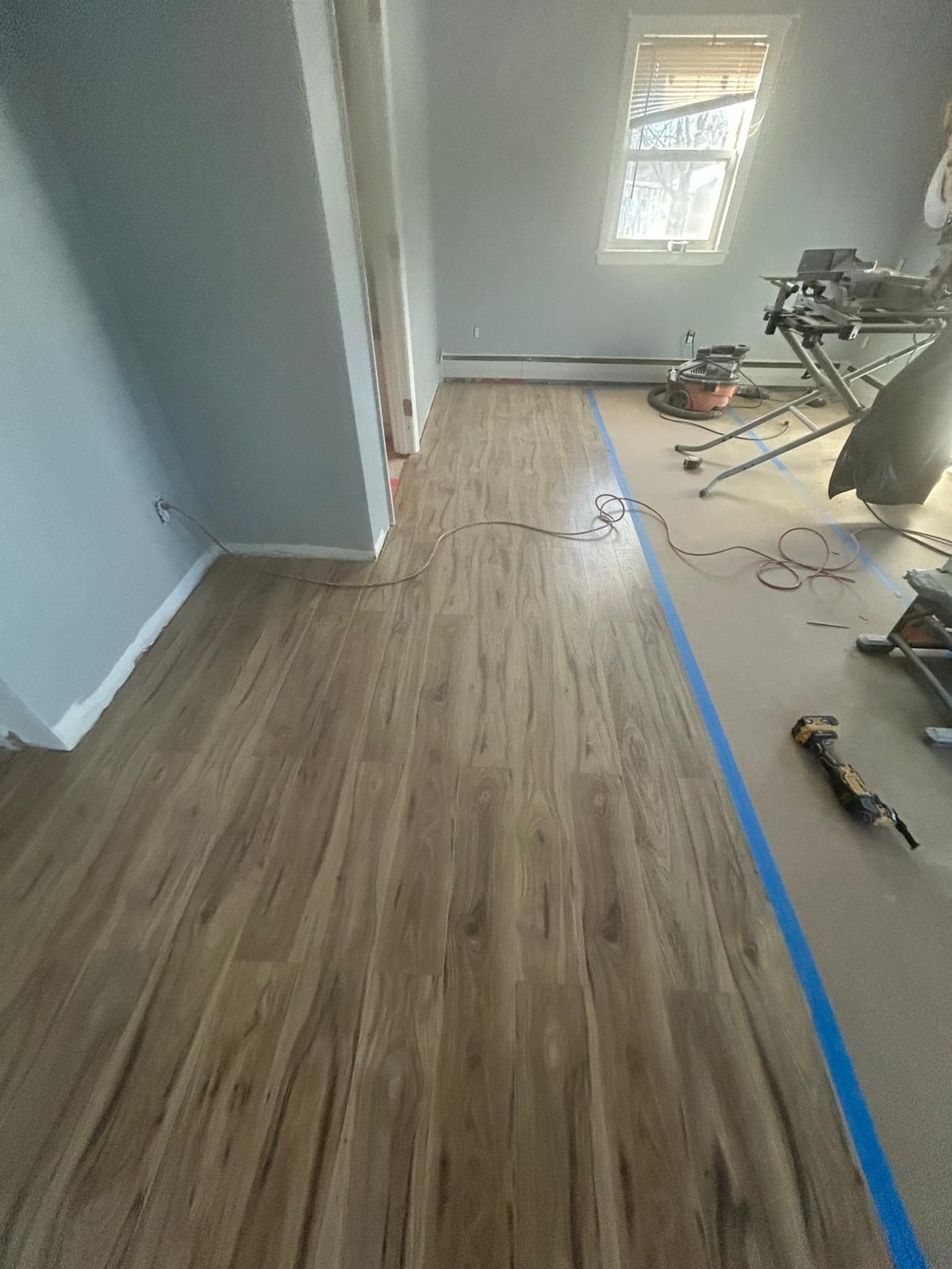 A room with a wooden floor and blue tape on the floor.