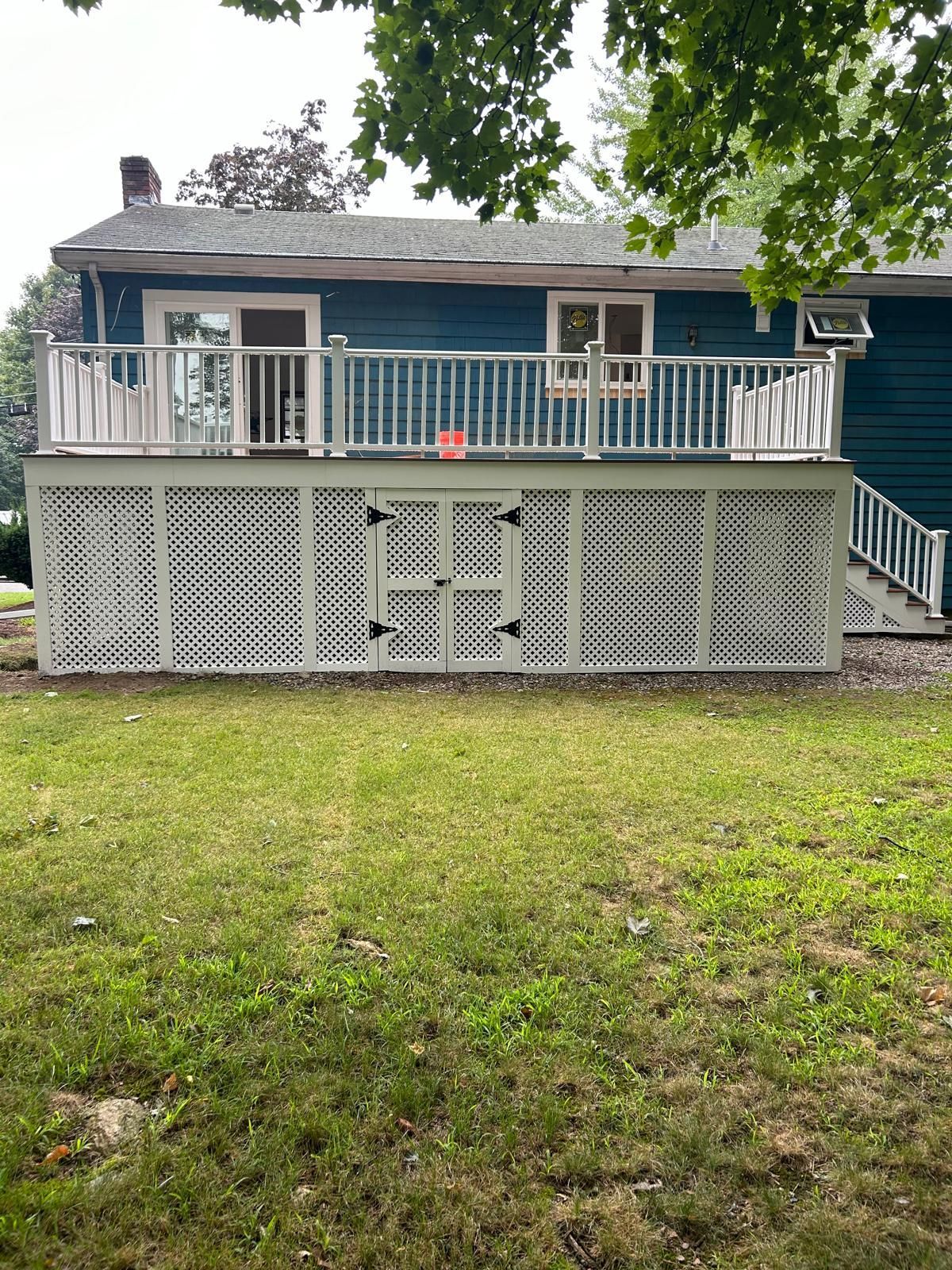 A blue house with a large deck and stairs in the backyard.