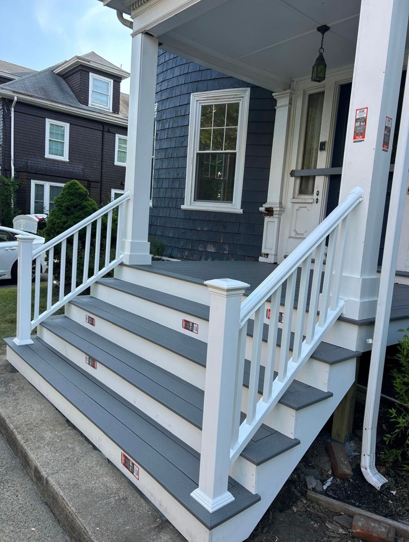 Gray steps with white railing leading to a house's front door, with blue siding.
