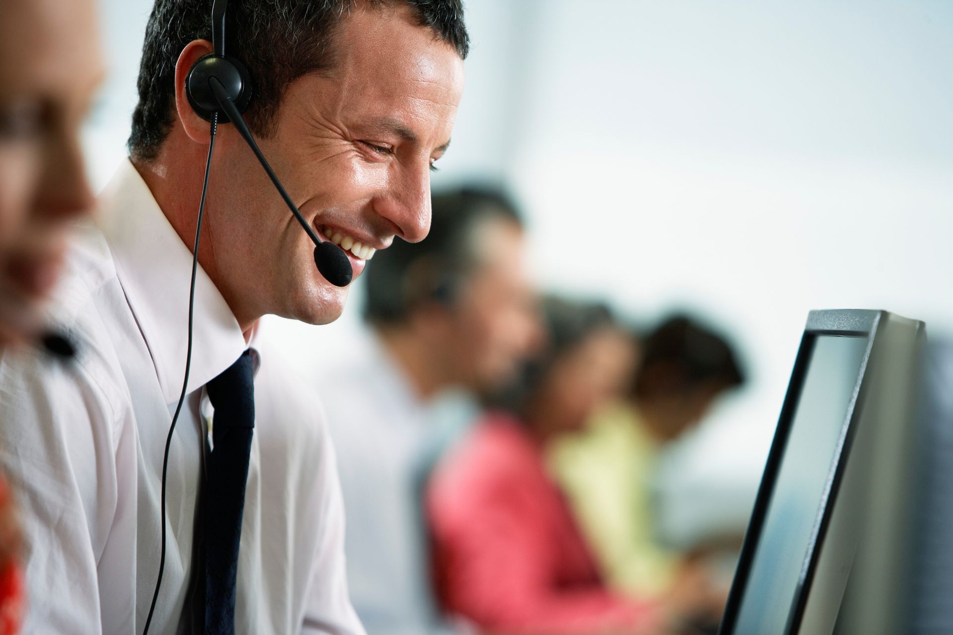 Woman wearing a headset and microphone, smiling at a laptop in a white background setting