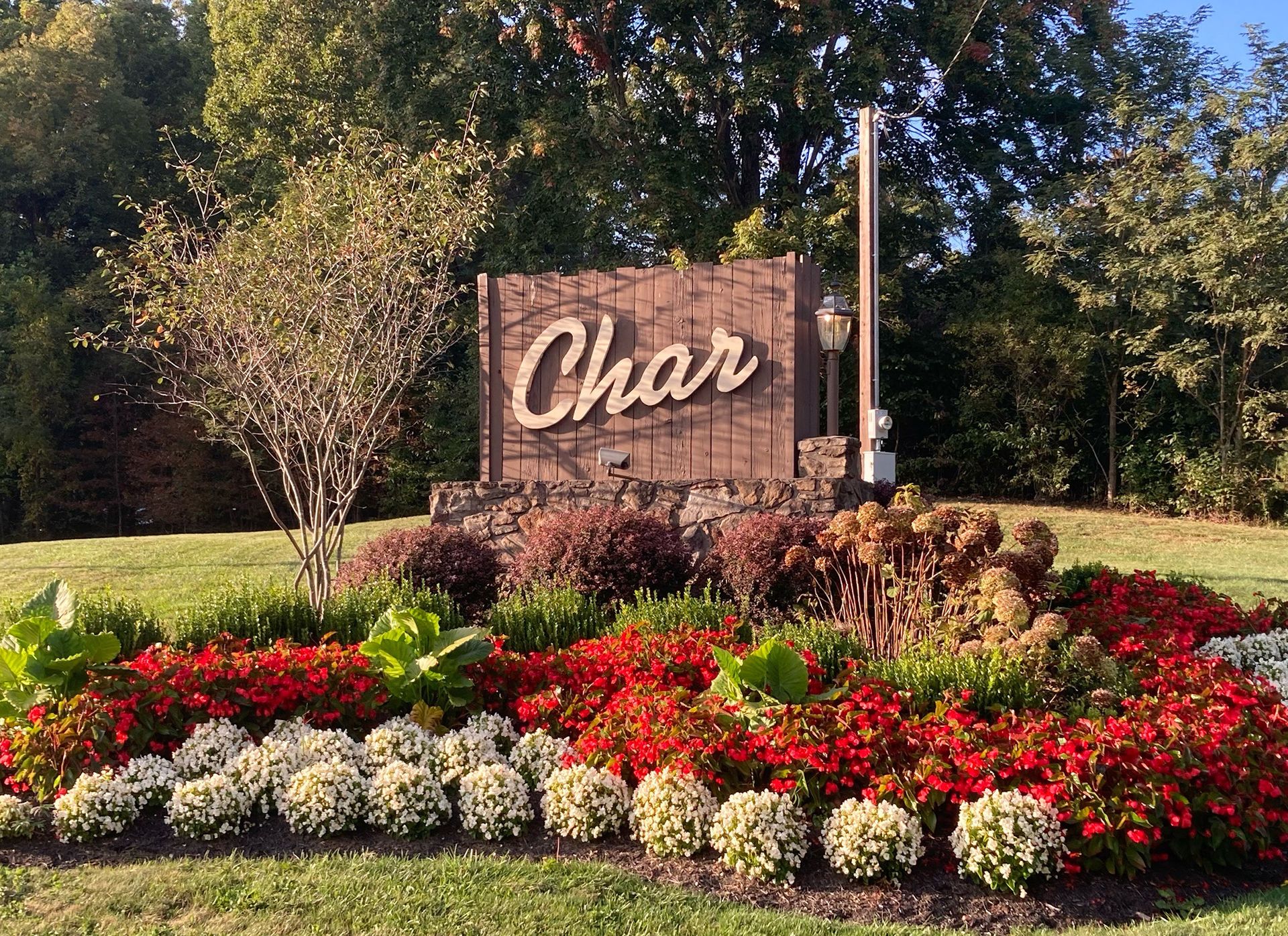 A sign for Char is surrounded by flowers in a garden.