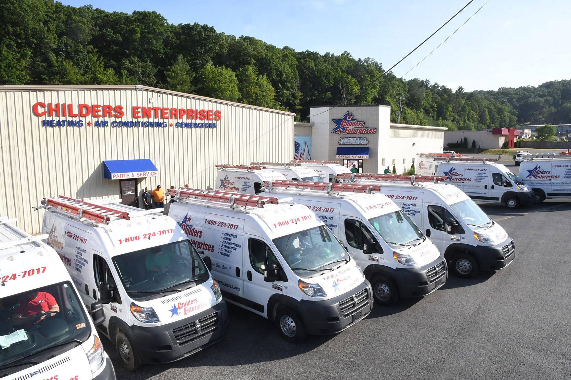 A row of vans parked in front of a building that says Childers Enterprises