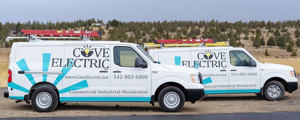 Two electric vans are parked next to each other on the side of the road.