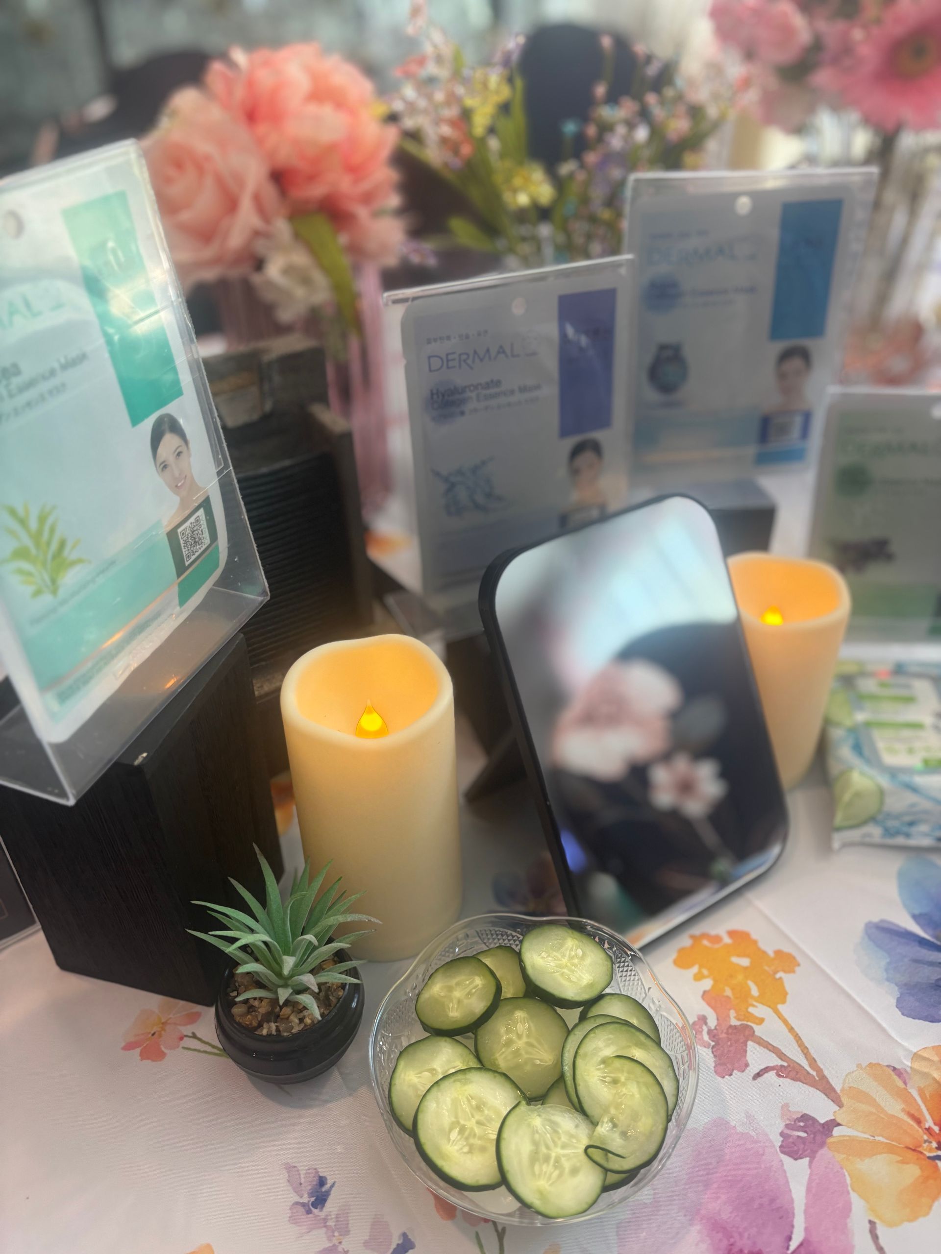 Memorial altar with candles, flowers, framed photos, and offerings including cucumbers and a small plant
