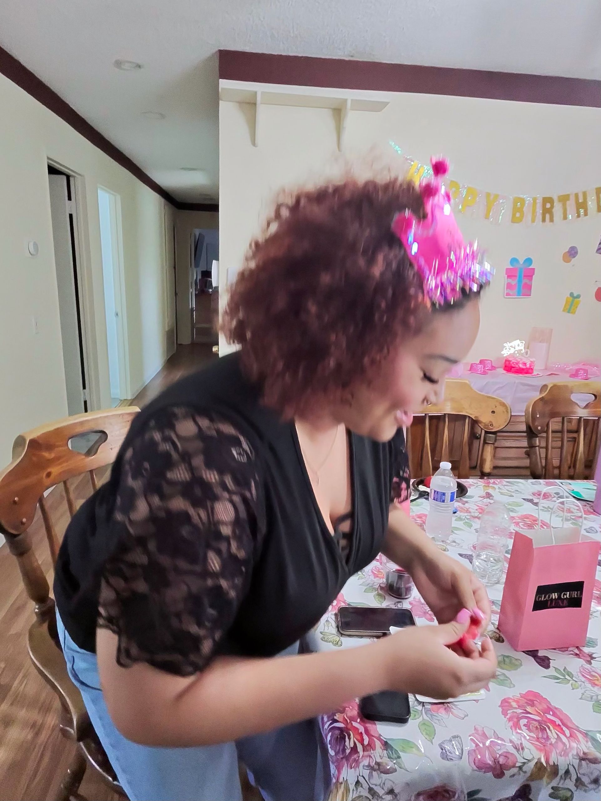 Woman in black lace top decorating a pink birthday table with confetti and gift boxes