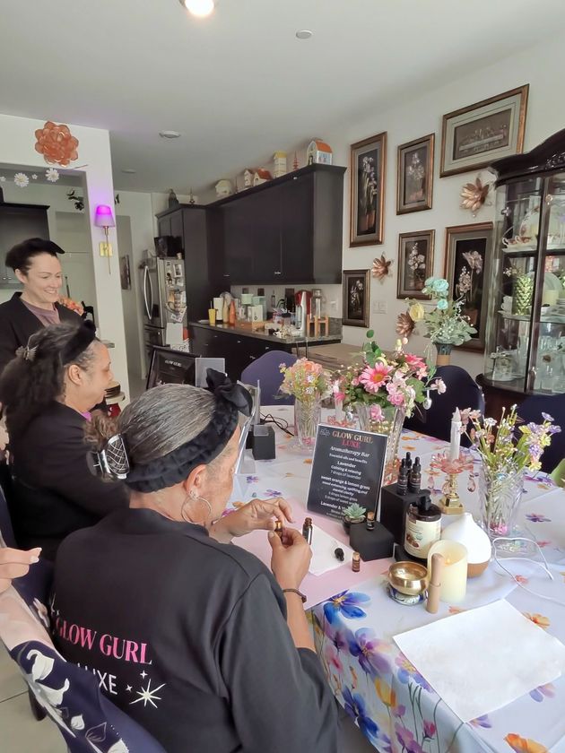 People seated at a decorated table in a home, facing a wall of framed photos and art.