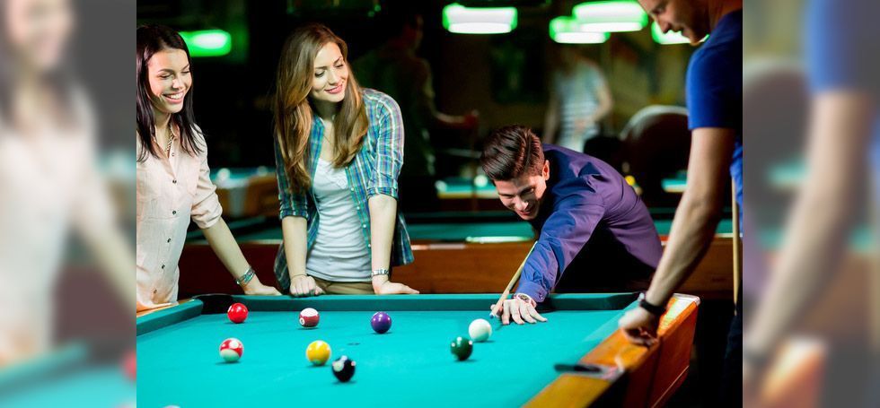 A group of people are playing pool in a pool hall.