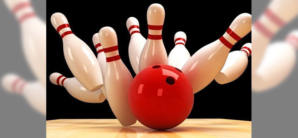 A red bowling ball is hitting white pins on a bowling alley