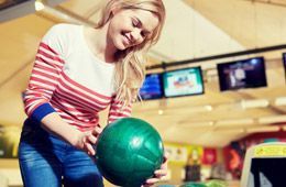A woman is holding a bowling ball in a bowling alley.