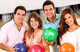 A group of people are holding bowling balls in a bowling alley.