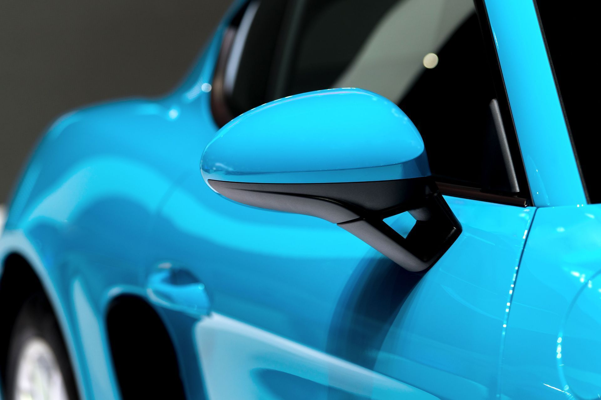 Close-up of a bright blue sports car’s side mirror and door