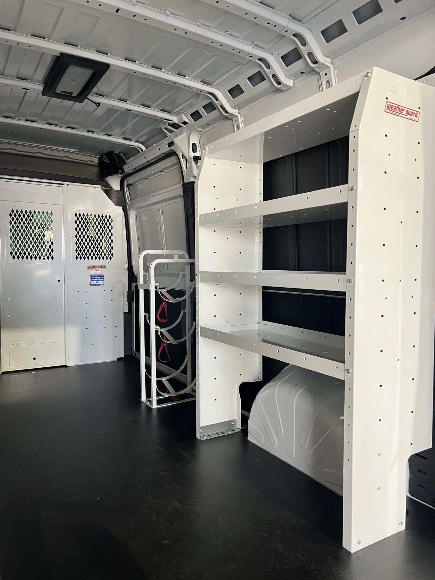 Interior of a white utility van with black floor, shelves, and rear doors visible