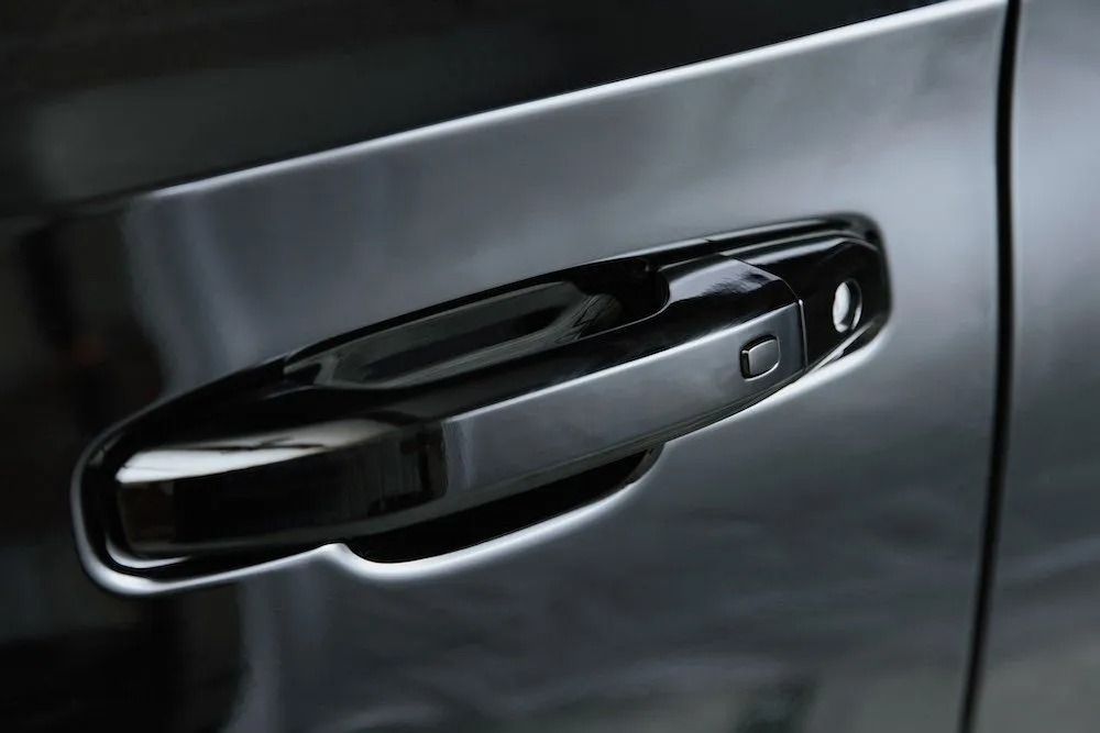 Close-up of a black car door handle on a dark vehicle.